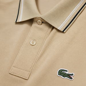 “Tan Lacoste polo shirt flat lay with striped collar and cuffs”